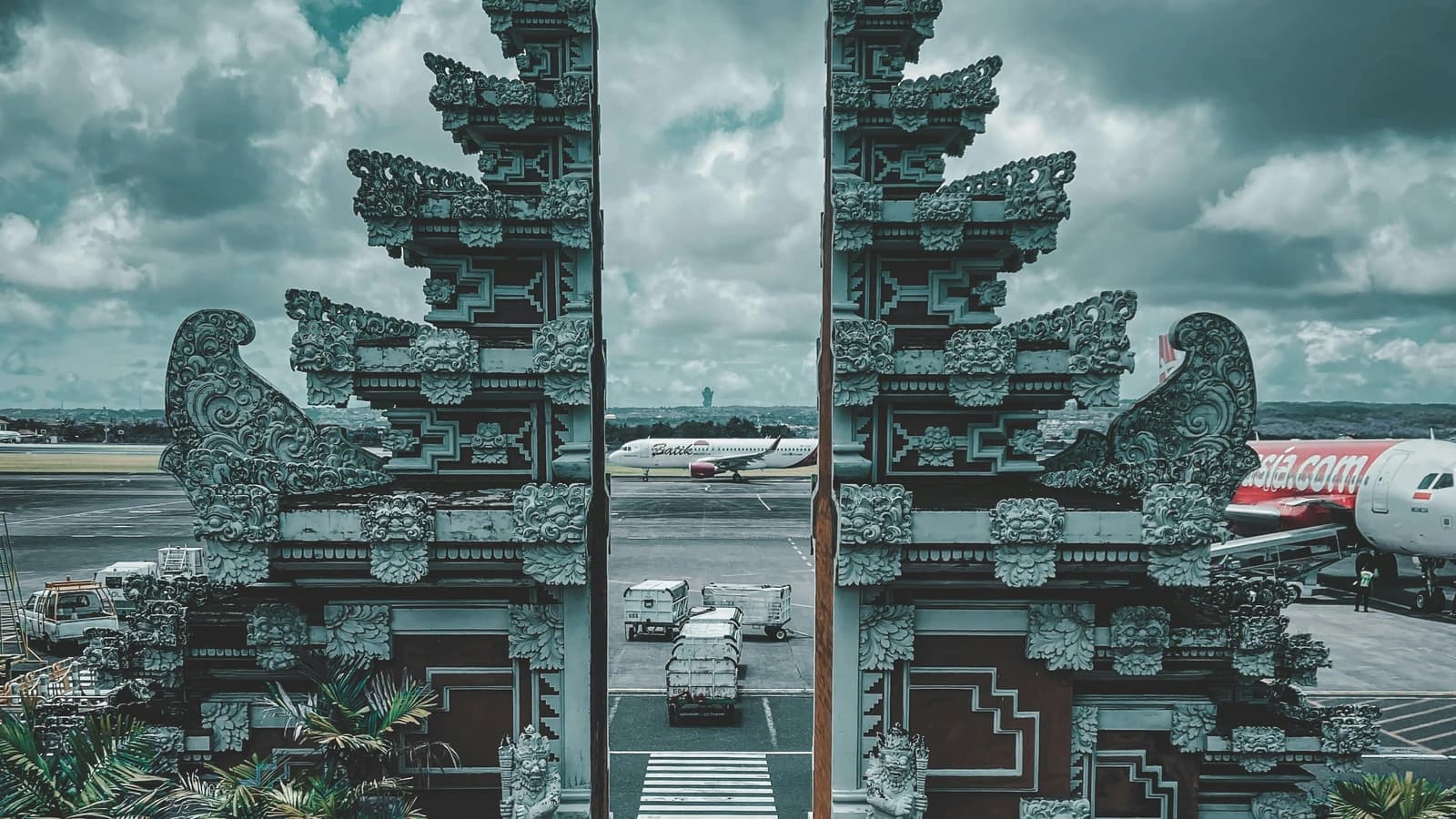 The traditional Balinese candi bentar gate framing the tarmac and aircraft at Ngurah Rai International Airport in Bali